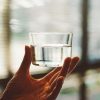 Person holding clear glass of drinking water