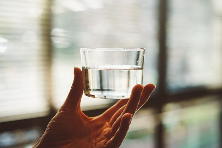 Person holding clear glass of drinking water